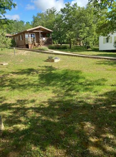 une cour avec une maison en arrière-plan avec une grande ombre dans l'établissement Domaine la cheneraie, à Mirabel