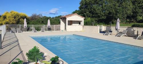 a large swimming pool with chairs and umbrellas at Domaine la cheneraie in Mirabel