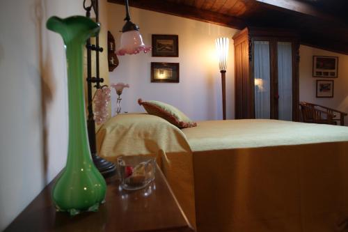 a green vase sitting on a table next to a bed at Akasamia B&B - La Dimora in Itri