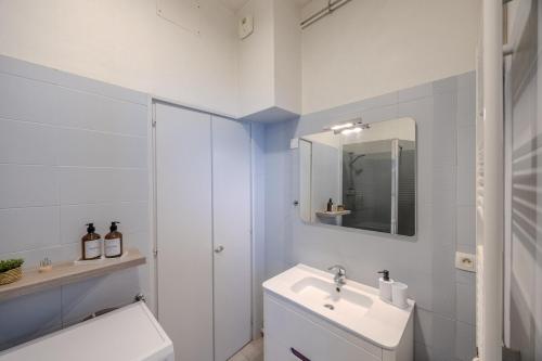 Un baño blanco con lavabo y espejo. en Grand appartement cosy - T3 en Hyper centre, en Mont-de-Marsan