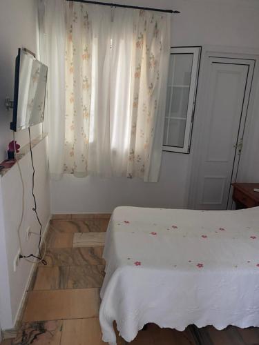 a bedroom with a bed and a television and a window at Hostal Restaurante La Niña in Palos de la Frontera