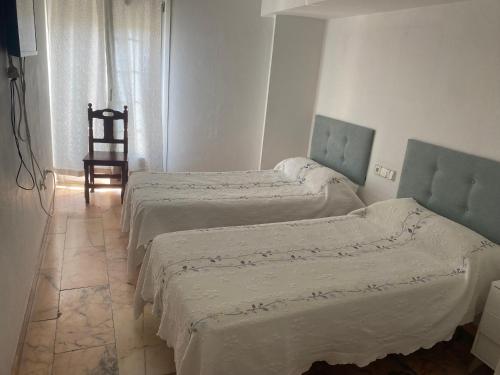 a bedroom with two beds and a chair in it at Hostal Restaurante La Niña in Palos de la Frontera