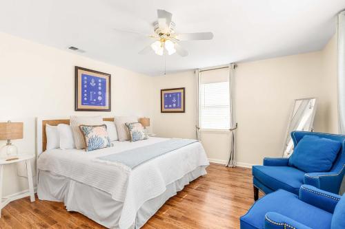 Un dormitorio con una cama blanca y una silla azul. en Bowline Bungalow, en Tybee Island