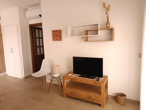a living room with a television and a table with a chair at Casa Smeralda Piano terra in Cannigione