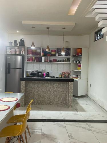 a kitchen with a counter and yellow chairs in it at Linda Casa a 25min da COP30 in Marituba