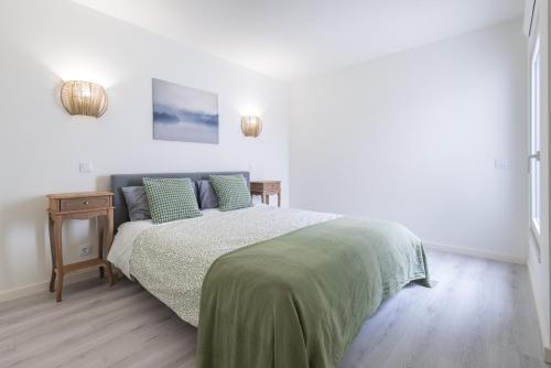 a white bedroom with a bed and a night stand at Peniche Hideout in Peniche