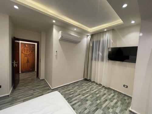 a room with a bed and a television and a door at Jewel Grand Pyramids Hotel in Cairo