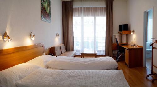 ein Hotelzimmer mit 2 Betten und einem Fenster in der Unterkunft Hotel Victoria in Brig