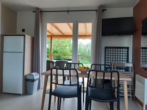 une cuisine avec une table, des chaises et un réfrigérateur dans l'établissement Les Lodges de l'Aubertière, à La Chapelle-Saint-Étienne