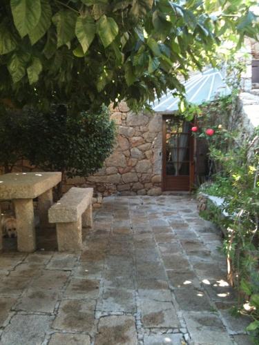 un patio avec deux bancs et une porte avec un bâtiment dans l'établissement Traditional Corsican house with private swimming pool, à Cauro