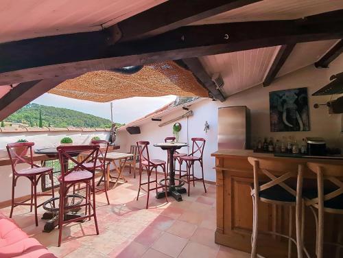 un bar avec des chaises et des tables rouges sur une terrasse dans l'établissement Le Sienna, Maison des Artistes, Vue, Rooftop, à Cotignac
