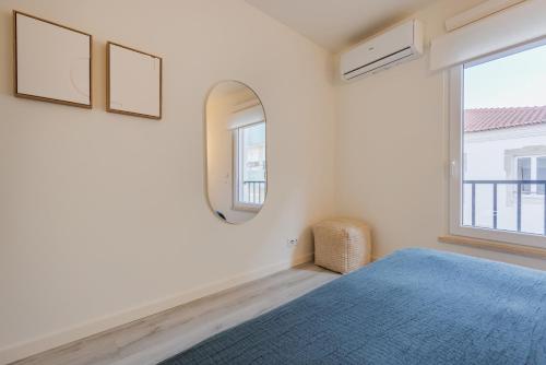 a bedroom with a blue bed and a mirror at Peniche Hideout in Peniche