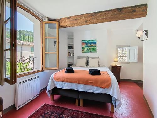 une chambre avec un lit et une grande fenêtre dans l'établissement Le Sienna, Maison des Artistes, Vue, Rooftop, à Cotignac