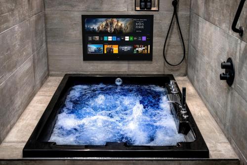 Luxury Old Town Apartment With Private Jacuzzi في إدنبرة: يوجد حوض جاكوزي في الحمام مع تلفزيون