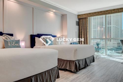 two beds in a room with a large window at Lucky Gem Penthouse & Luxury Suites at Signature Resort, Strip View 509 in Las Vegas