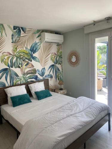 - une chambre avec un grand lit et du papier peint tropical dans l'établissement Les Oliviers, à Villemoustaussou