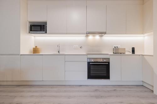 a kitchen with white cabinets and a sink and a stove at Peniche Hideout in Peniche