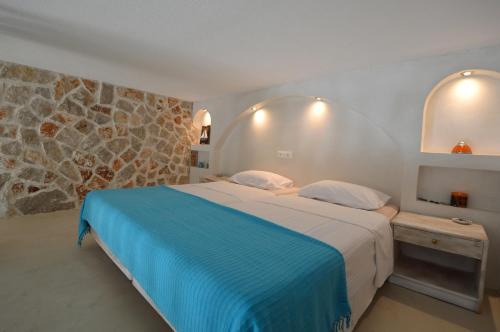 a bedroom with a bed and a stone wall at Kathara Bay Apartments in Faliraki