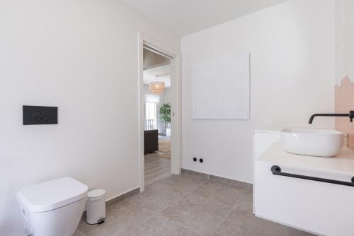 a white bathroom with a toilet and a sink at Peniche Hideout in Peniche