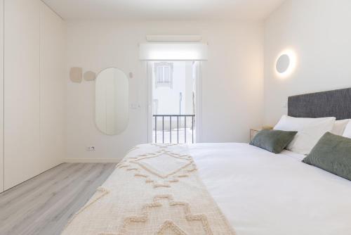 a white bedroom with a large white bed with green pillows at Peniche Hideout in Peniche