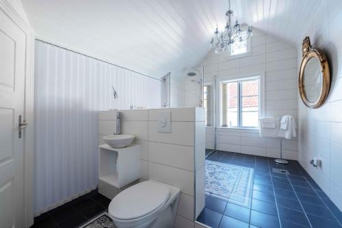 a white bathroom with a toilet and a sink at Lundins Hotell in Karmøy