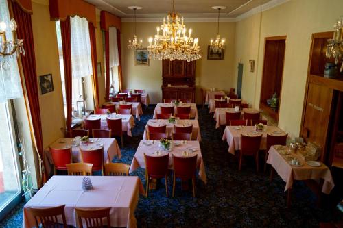 un comedor con mesas y sillas y una lámpara de araña en Hotel Victoria, en Brig