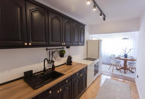 a kitchen with black cabinets and a sink and a table at Lima 5th apartment in Novi Pazar