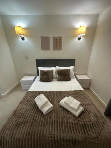 a bedroom with a large bed with two towels on it at Luxury One Bedroom Flat next to Wembley Stadium in London