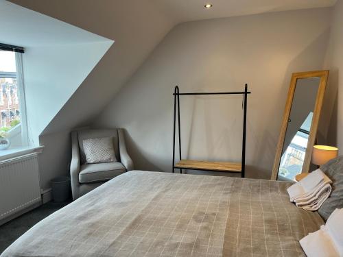 a bedroom with a bed and a chair and a mirror at Fairfield Cottage Rooms in Inverness
