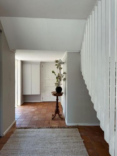 a hallway with a staircase with a vase on a table at Gatans Gård sekelskiftshus 