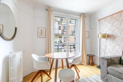 une petite salle à manger avec une table et une fenêtre dans l'établissement Appartement Neuilly Chic, Vivez l'Élégance - II, à Neuilly-sur-Seine