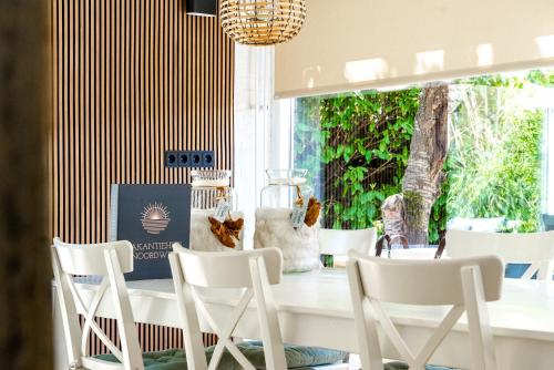 a dining room with white chairs and a table at -Duna Lago- nabij het meer, restaurants en Keukenhof in Noordwijkerhout