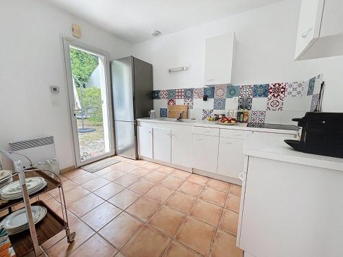 une cuisine avec des armoires blanches et un sol carrelé dans l'établissement Maison bourg de Saint Pierre Oleron, à Saint-Pierre-dʼOléron