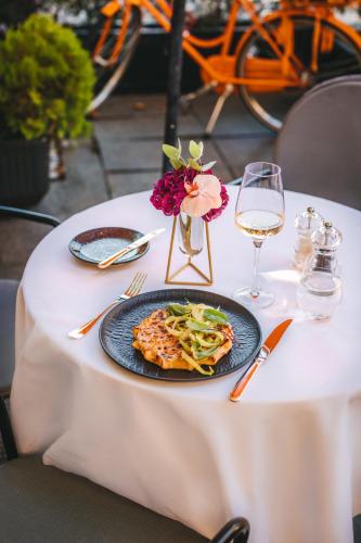 a table with a plate of pasta and a glass of wine at Esplanade Zagreb Hotel in Zagreb