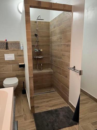 La salle de bains est pourvue de toilettes et d'une douche avec des murs en bois. dans l'établissement Les hauts d'Ou Souleou, villa contemporaine 8 personnes, piscine à débordement, jacuzzi intégré, très belle vue mer et collines, à Bormes-les-Mimosas