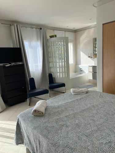 - une chambre avec un lit et deux chaises et une salle de bains dans l'établissement Les hauts d'Ou Souleou, villa contemporaine 8 personnes, piscine à débordement, jacuzzi intégré, très belle vue mer et collines, à Bormes-les-Mimosas