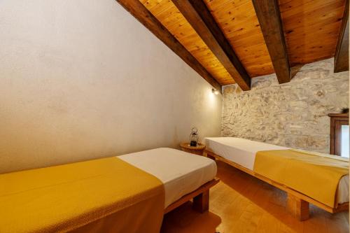 two beds in a room with a stone wall at Santa Teresa in Erice