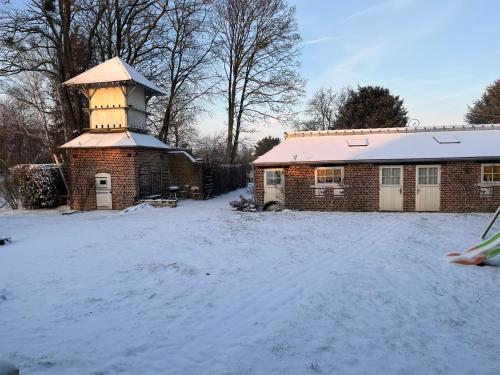un bâtiment en briques avec une tour dans la neige dans l'établissement Gîte du petit jardin, à Annois
