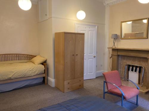 1 dormitorio con 1 cama, 1 silla y chimenea en Gilmore Flat, en Edimburgo