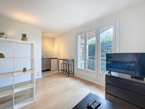 un salon avec une télévision et une grande fenêtre dans l'établissement Studio 2 personnes avec parking et balcon Proudhon, à Clermont-Ferrand