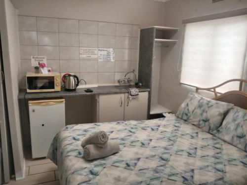 a bedroom with a bed and a kitchen with a microwave at B@home in Bloemfontein