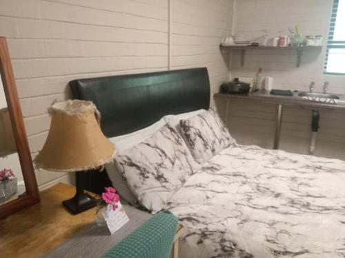 a bedroom with a bed with a lamp and a table at B@home in Bloemfontein