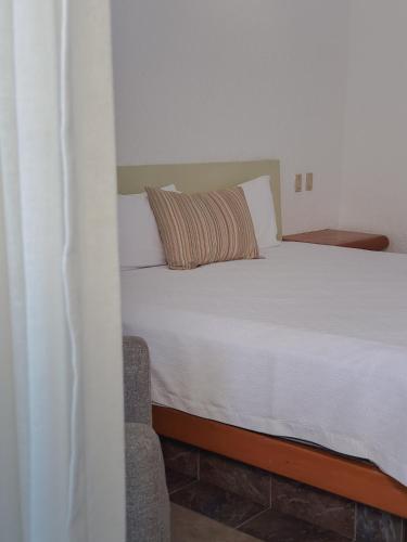a bedroom with a white bed with a pillow at Hotel Los Patios in Cabo San Lucas