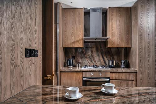 a kitchen with wooden cabinets and a table with two cups at FIVE Palm Jumeirah Premier Apartments in Dubai