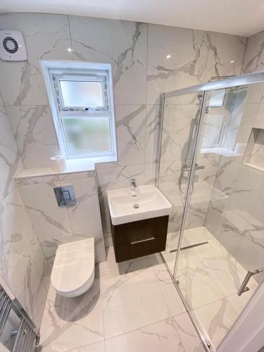 a bathroom with a sink and a shower and a toilet at 2-Bedroom Garden Flat - Modern, Bright - A in London