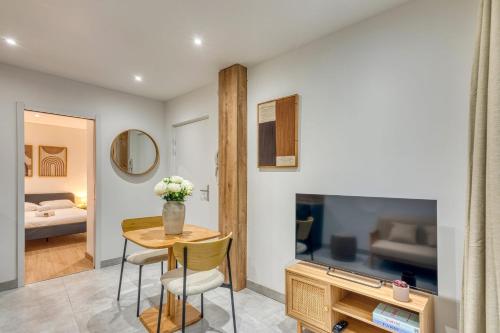 a living room with a table and a tv at Le Bois Doré - Cosy - Sainte-Foy-Les-Lyon in Sainte-Foy-lès-Lyon