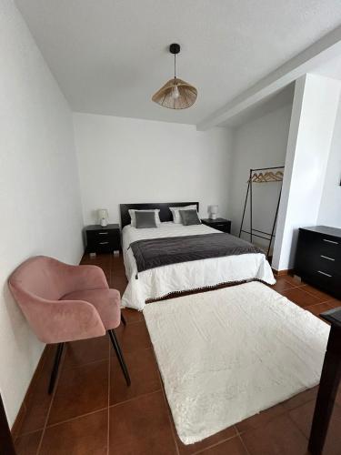 a bedroom with two beds and a pink chair at Celina Residence in Ribeira Brava