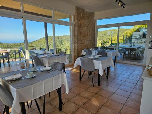 a restaurant with white tables and chairs and large windows at La Roqueta Hotel in Tossa de Mar