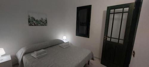 a small bedroom with a bed and a door at Villa con giardino sul lungomare in Campofelice di Roccella