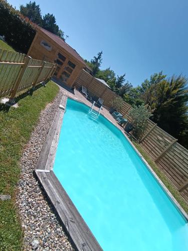 une grande piscine avec une terrasse en bois et une eau bleue dans l'établissement Gîte les Clairieres - Piscine, Climatisation, à Cauzac